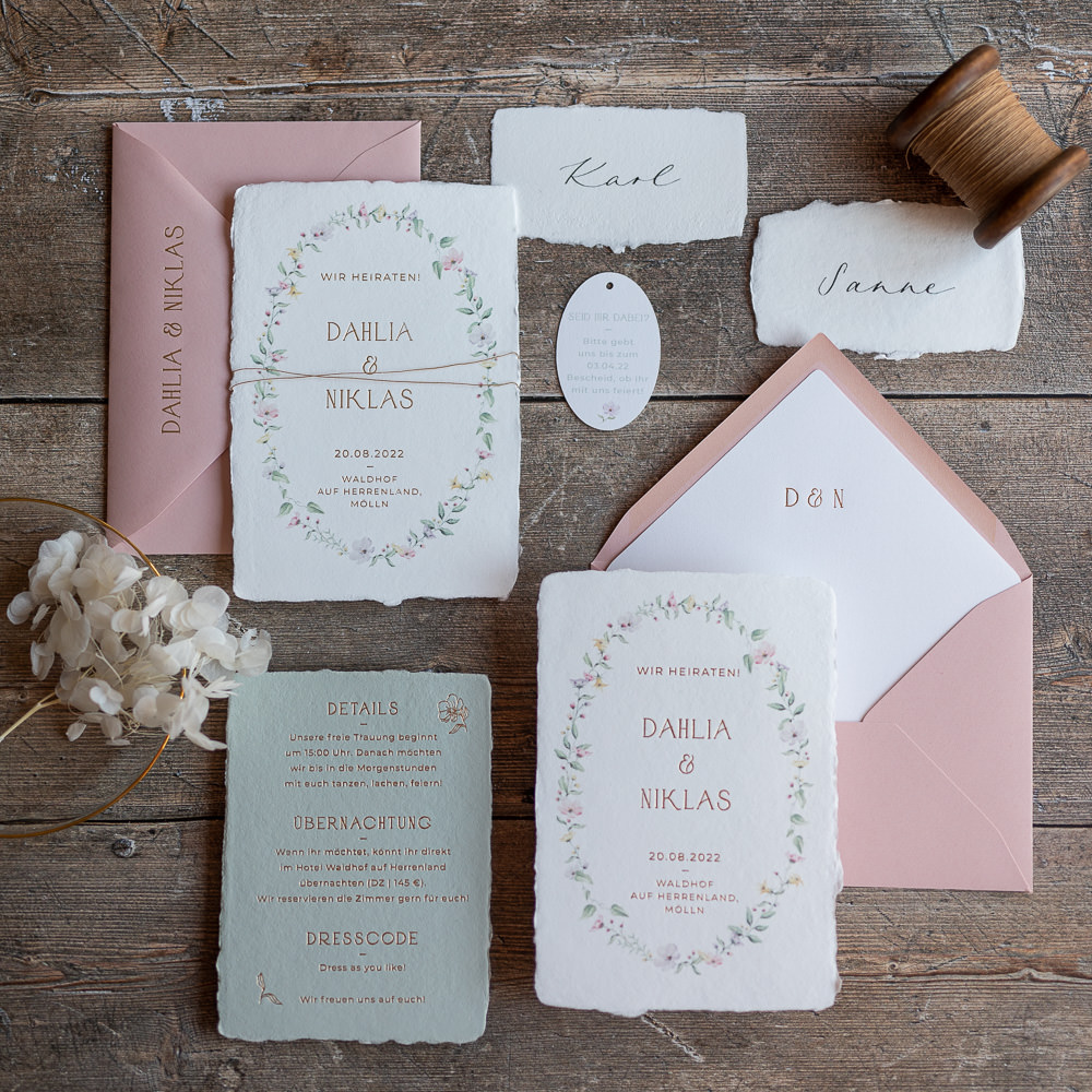 Ein Flatley von einem Hochzeitspapeterie Set mit handgeschöpftem Papier, einem Blumenkranz und Goldprägung.
